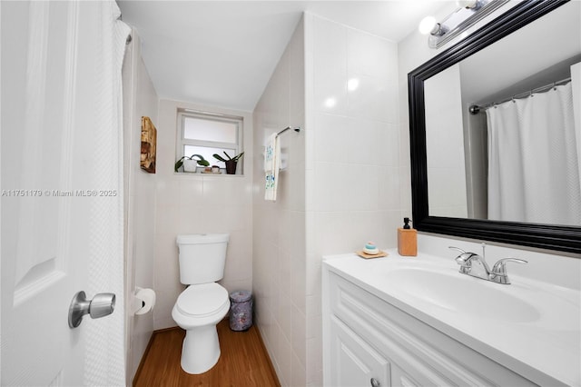 full bath featuring wood finished floors, tile walls, toilet, and vanity