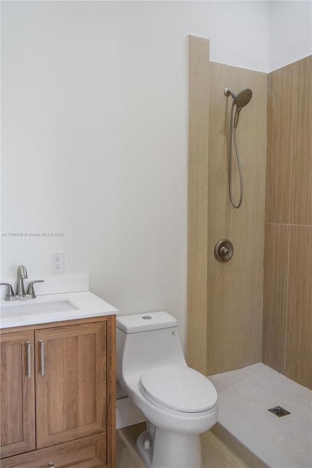 full bathroom featuring vanity, a tile shower, and toilet