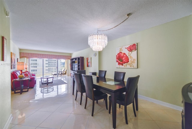 dining space featuring baseboards, a chandelier, a textured ceiling, and light tile patterned flooring