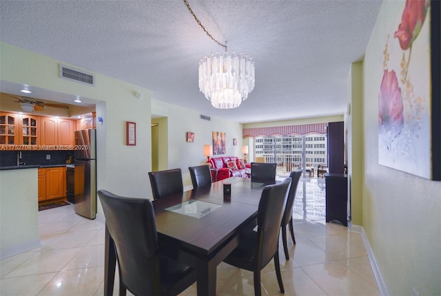 dining room with a chandelier, a textured ceiling, light tile patterned flooring, and visible vents