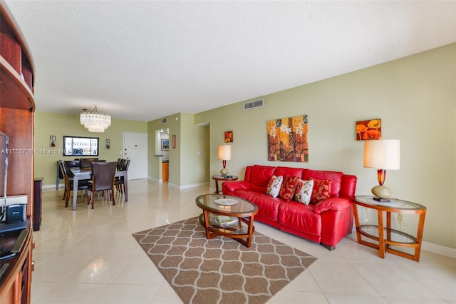 living area featuring visible vents, a textured ceiling, a chandelier, tile patterned flooring, and baseboards