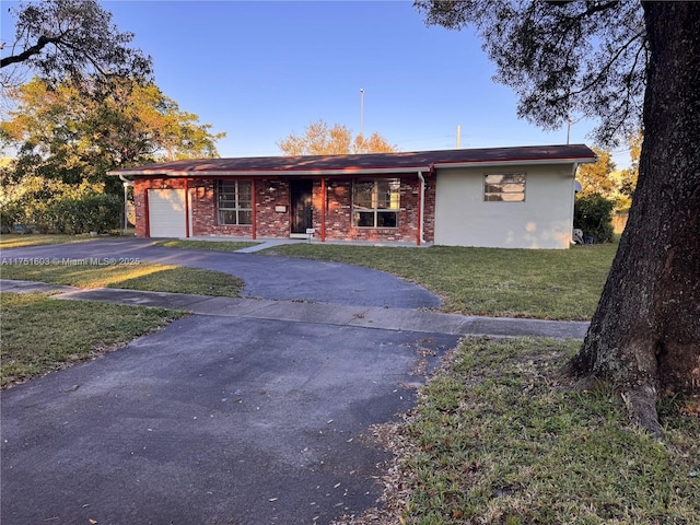 ranch-style house featuring a garage, a front yard, aphalt driveway, and brick siding