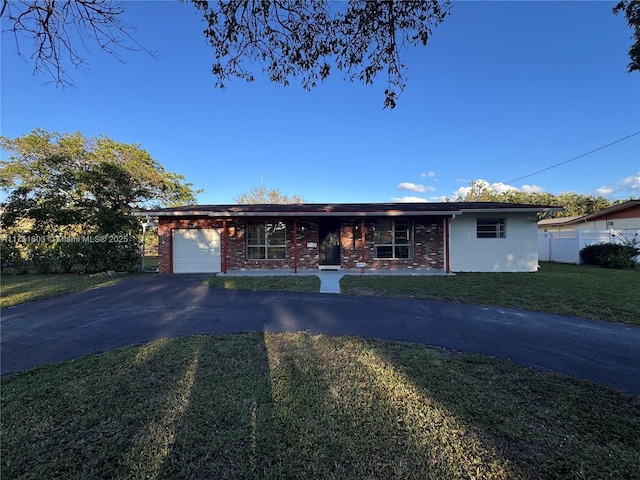 ranch-style home with brick siding, fence, a garage, driveway, and a front lawn