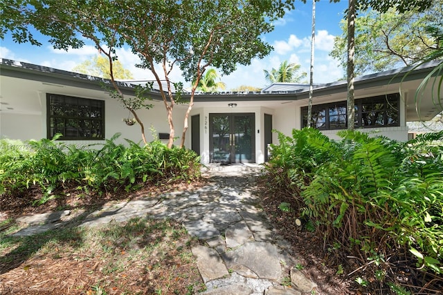 rear view of house with french doors and stucco siding