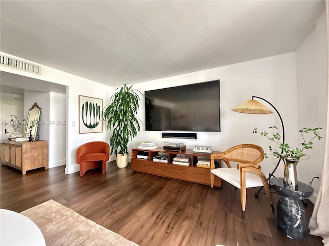 living room with dark wood-style floors, visible vents, and baseboards