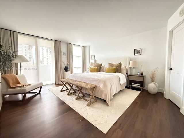 bedroom featuring a wall of windows, access to outside, baseboards, and wood finished floors