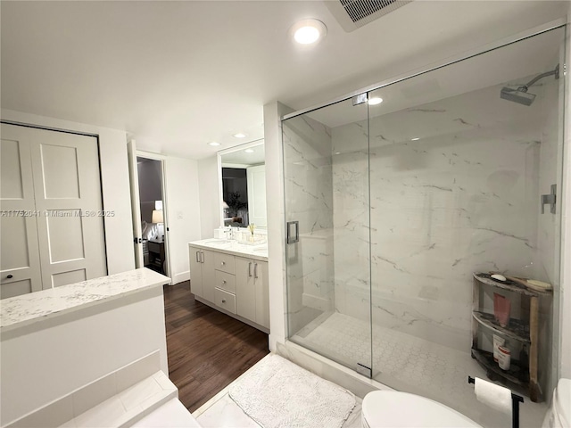 ensuite bathroom featuring a marble finish shower, double vanity, visible vents, ensuite bathroom, and wood finished floors