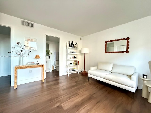 living area featuring visible vents, dark wood finished floors, and baseboards