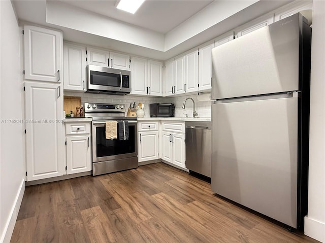 kitchen featuring appliances with stainless steel finishes, light countertops, white cabinetry, and dark wood-type flooring