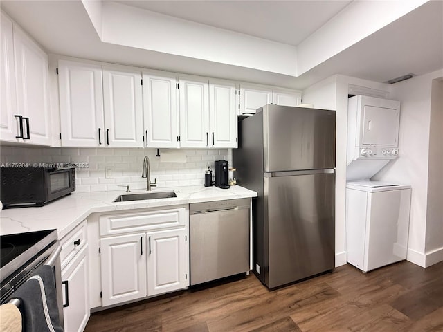 kitchen featuring stainless steel appliances, a sink, white cabinetry, and stacked washer / drying machine