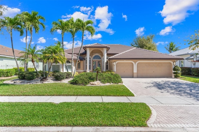 5135 Kensington Cir, Coral Springs, FL 33076 - mediterranean / spanish-style home with an attached garage, decorative driveway, a front lawn, stucco siding, and a tile roof