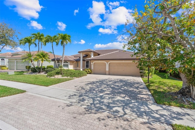 view of front facade with decorative driveway, stucco siding, a front yard, a garage, and a tiled roof