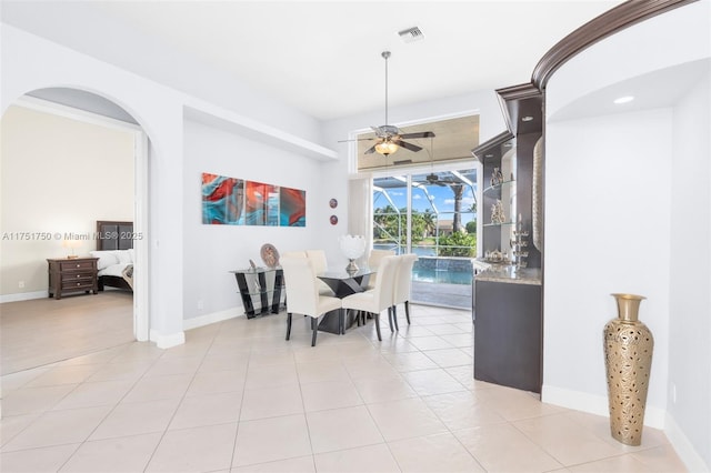 dining area with light tile patterned floors, a sunroom, and baseboards