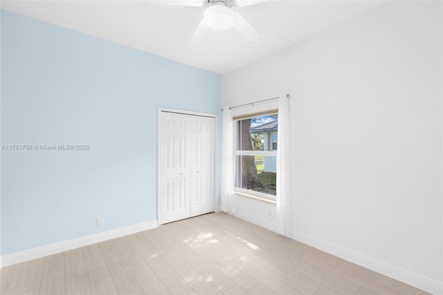 unfurnished bedroom featuring ceiling fan, a closet, light wood-style flooring, and baseboards