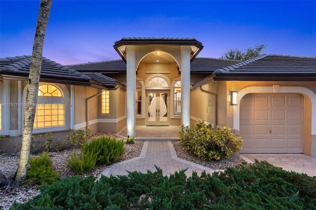 5135 Kensington Cir, Coral Springs, FL 33076 - view of exterior entry with a garage, a tile roof, stucco siding, and french doors