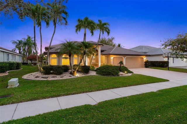 view of front of property featuring driveway, a tile roof, an attached garage, a front yard, and stucco siding