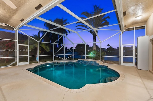 pool at dusk featuring a lanai, a patio area, and an outdoor pool