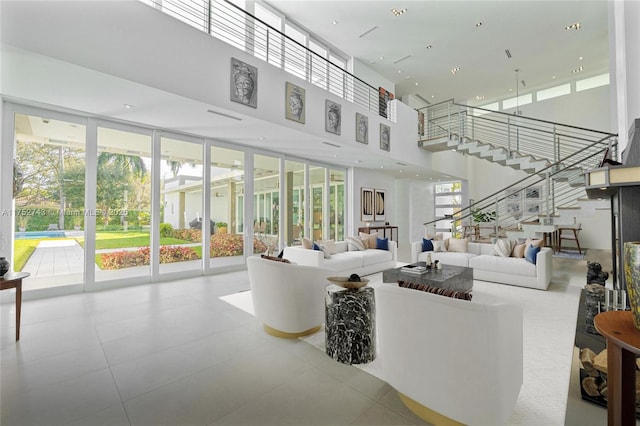 living area with expansive windows, a high ceiling, stairway, and recessed lighting