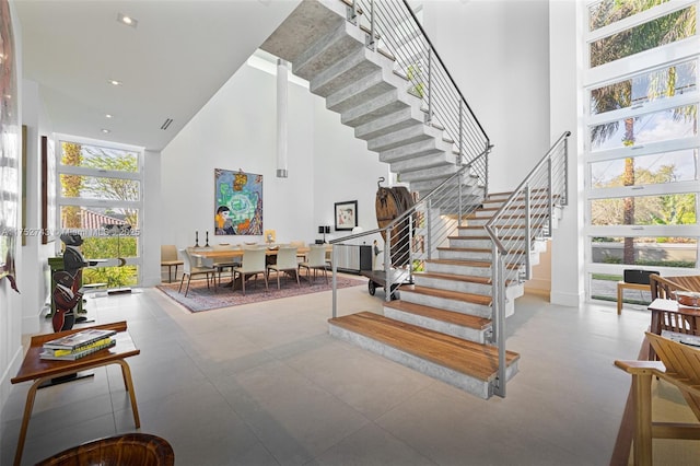 foyer with stairway, expansive windows, a towering ceiling, and recessed lighting