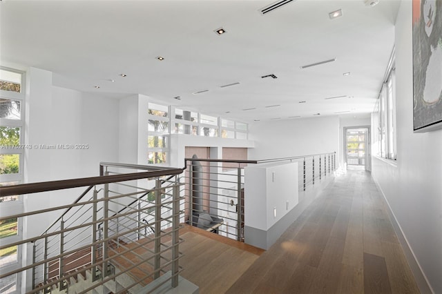 hall featuring baseboards, an upstairs landing, and wood finished floors