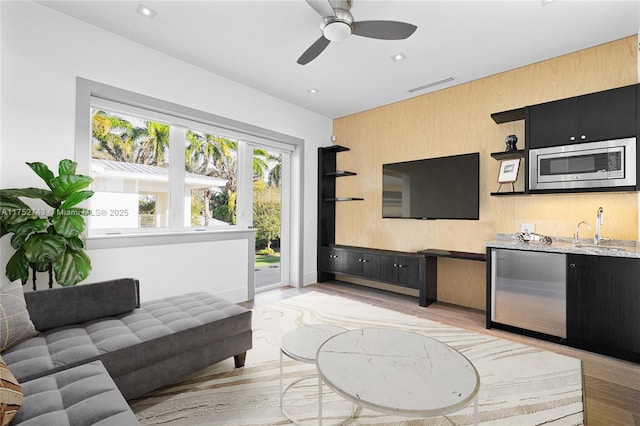 living area with recessed lighting, visible vents, light wood-style floors, ceiling fan, and wet bar