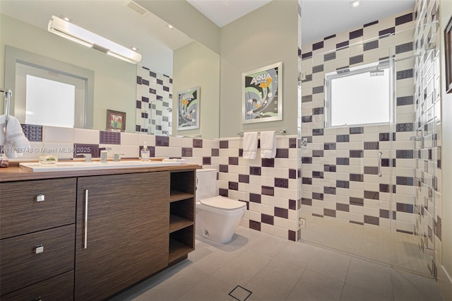 full bathroom with tile walls, double vanity, toilet, a shower stall, and tile patterned floors