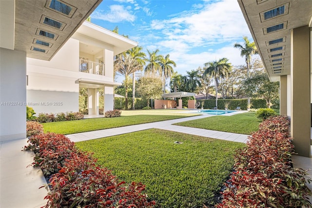 view of yard with a balcony and a fenced in pool