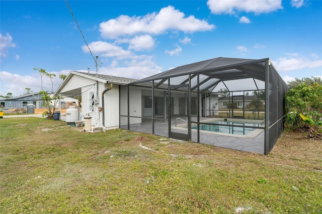 rear view of property featuring glass enclosure, a lawn, a patio area, and an outdoor pool