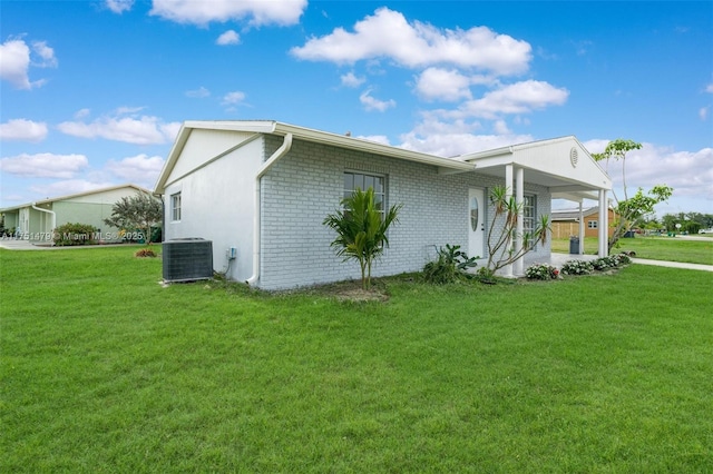 view of home's exterior featuring a yard, brick siding, and central AC