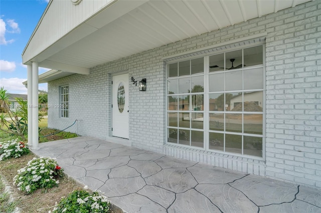 view of exterior entry with brick siding and a patio area