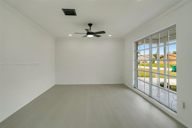 empty room with ornamental molding, wood finished floors, visible vents, and baseboards