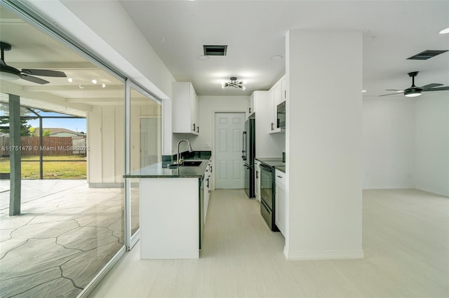 kitchen featuring a sink, visible vents, white cabinets, black appliances, and dark stone countertops