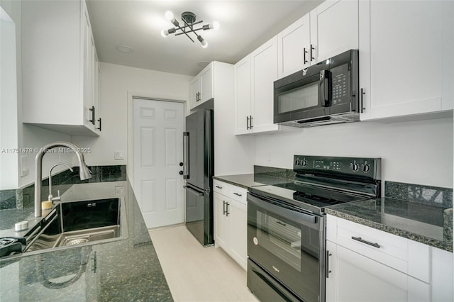 kitchen featuring black appliances, dark stone countertops, white cabinets, and a sink