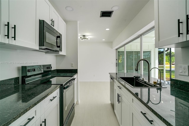 kitchen featuring dark stone countertops, white cabinets, and black appliances