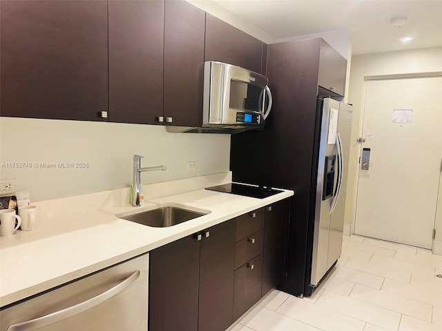 kitchen featuring recessed lighting, a sink, light countertops, appliances with stainless steel finishes, and dark brown cabinets