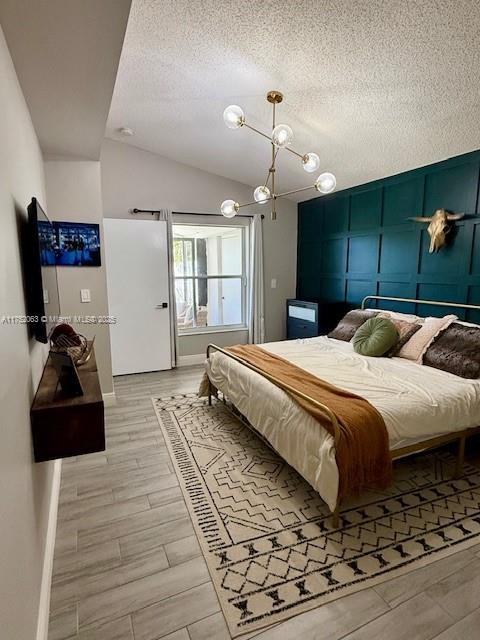 bedroom with wood tiled floor, baseboards, vaulted ceiling, and a textured ceiling