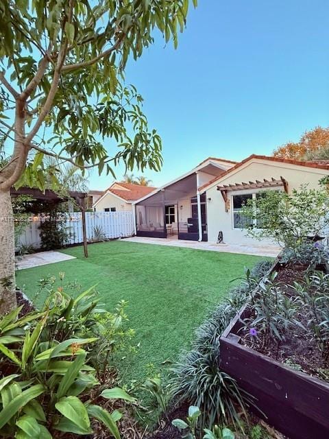 view of yard featuring a patio, a vegetable garden, a sunroom, and fence