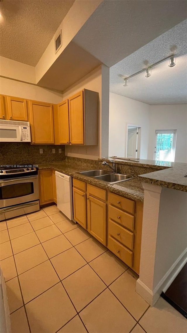 kitchen featuring white appliances, light tile patterned floors, visible vents, a textured ceiling, and a sink