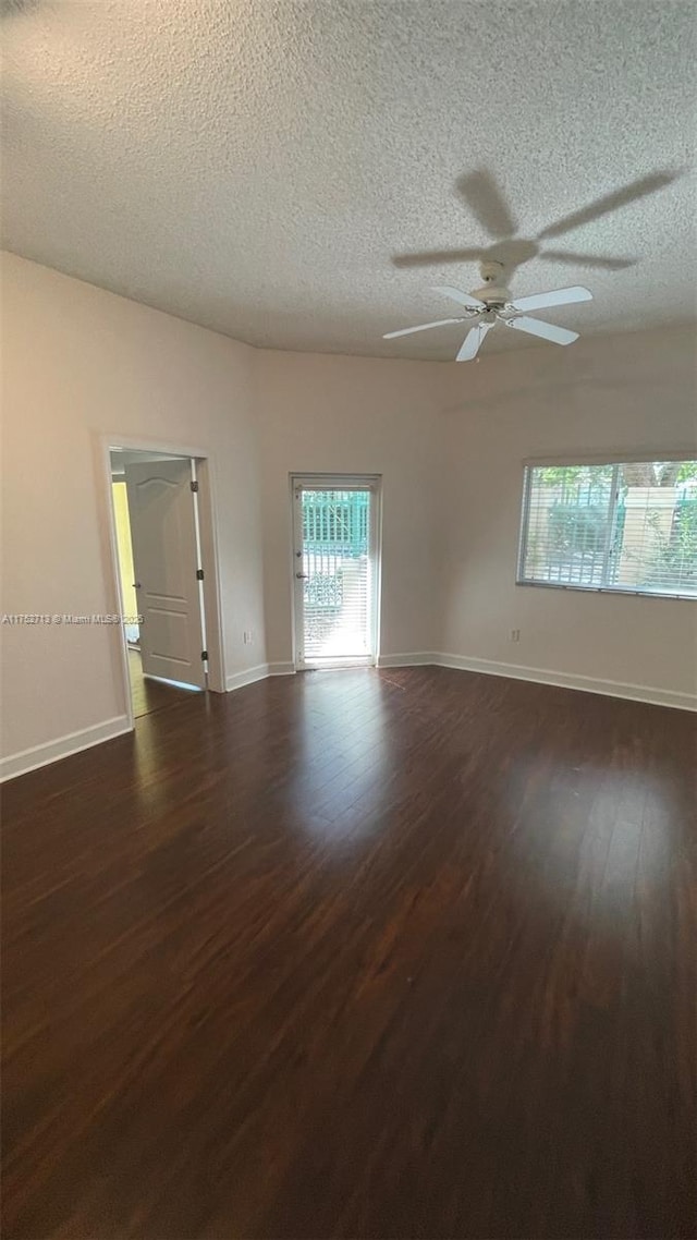 unfurnished room featuring dark wood-style floors, a ceiling fan, baseboards, and a textured ceiling