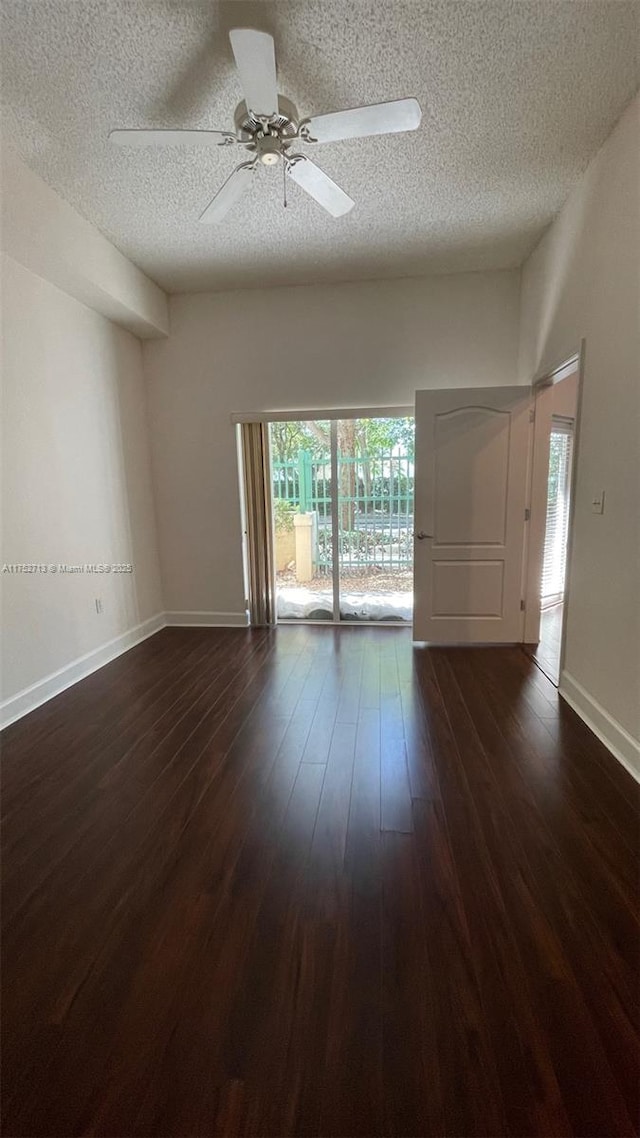 unfurnished room with dark wood-style floors, ceiling fan, baseboards, and a textured ceiling