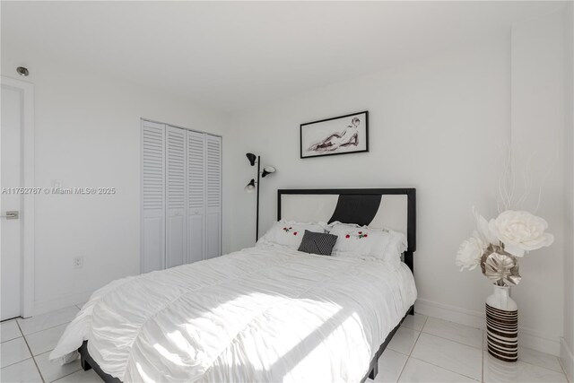 bedroom featuring a closet, baseboards, and light tile patterned floors