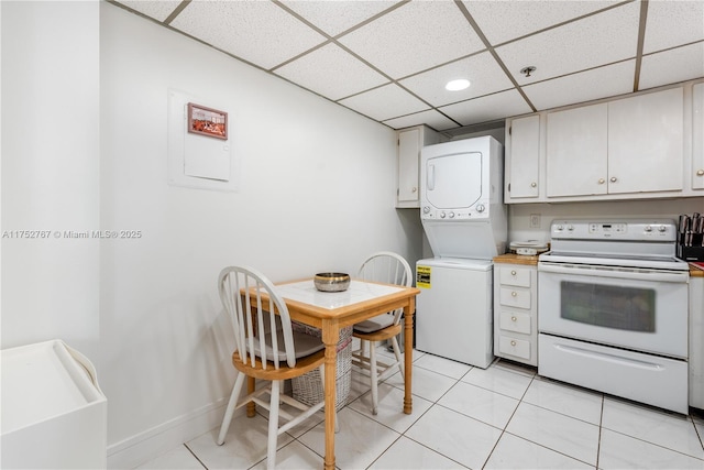 kitchen featuring light tile patterned floors, a paneled ceiling, stacked washer and dryer, light countertops, and white electric range oven