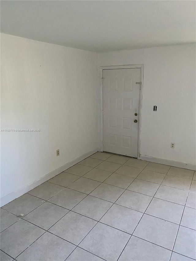 spare room featuring baseboards and light tile patterned floors