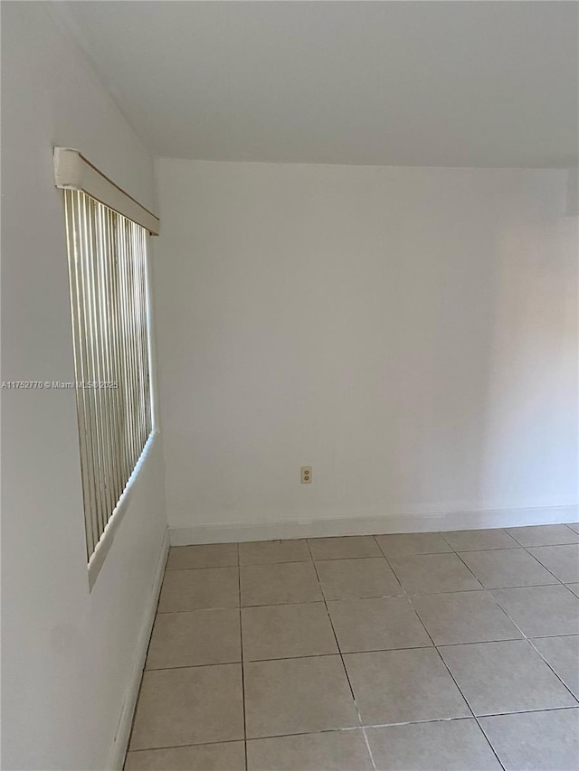 unfurnished room with light tile patterned floors and baseboards