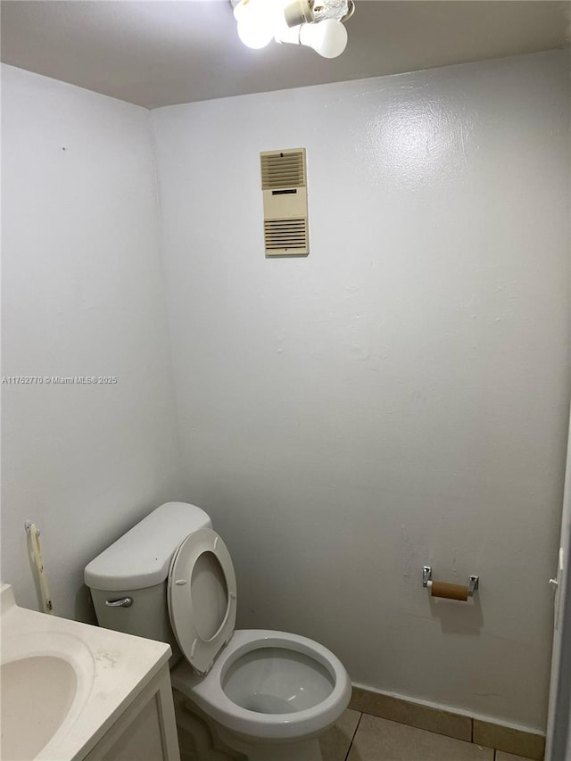 half bathroom featuring baseboards, visible vents, toilet, tile patterned floors, and vanity