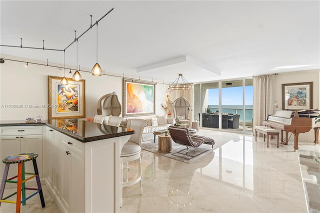 kitchen with open floor plan, a water view, a kitchen bar, and white cabinetry