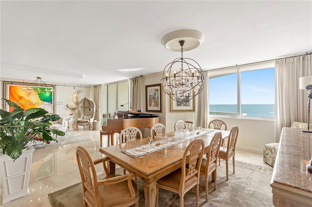 dining space with baseboards, a water view, a view of the beach, and an inviting chandelier