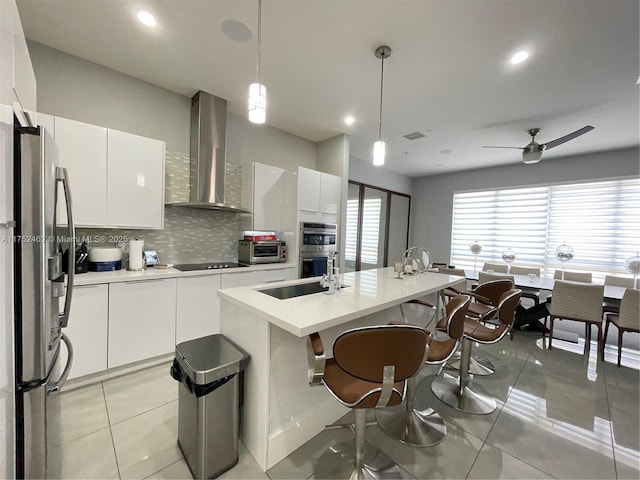 6651 NW 105th Pl Unit 6651, Doral, FL 33178 - kitchen with appliances with stainless steel finishes, wall chimney range hood, tasteful backsplash, white cabinets, and recessed lighting