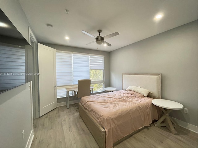 bedroom with ceiling fan, light wood-style flooring, and baseboards