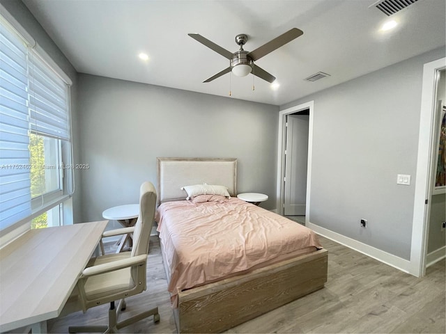 bedroom featuring a ceiling fan, wood finished floors, visible vents, and baseboards